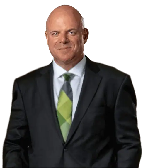 A man in a suit with a green tie stands facing forward, smiling slightly.