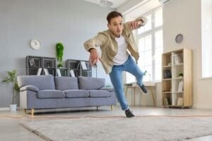 Man tripping over extension cord in living room near sofa and rug