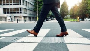 businessman in dress shoes and suit walking across urban crosswalk