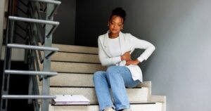 woman seated on stairs clutching side after falling near dropped clipboard