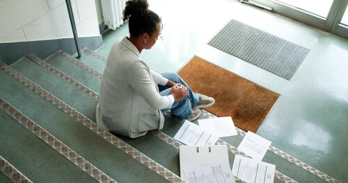 woman seated on stairs after fall with scattered documents on floor